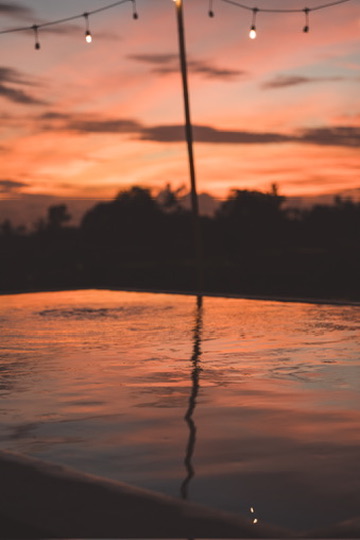 Desa Kayu pool at dusk, string lights reflected in the water